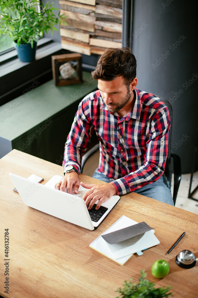 Young businessman working on laptop at office. Businessman sitting at office desk working on new project. Young businessman working on laptop at office. Businessman sitting at office desk working on new project.