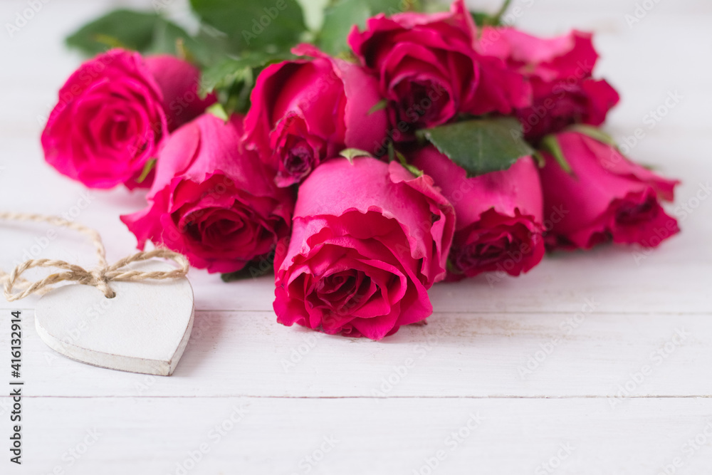 Bunch of pink roses and white wooden heart on wooden table Bunch of pink roses and white wooden heart on wooden table
