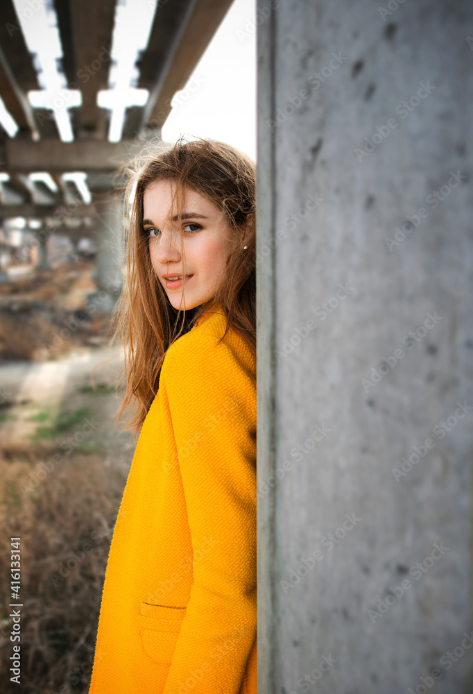 young girl in a yellow coat at an abandoned construction site. city ​​landscape.
