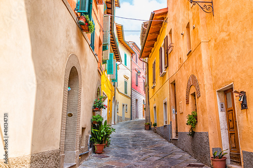 Fototapeta Naklejka Na Ścianę i Meble -  Chiusi, Italy narrow street alley in small historic medieval town village in Tuscany during sunny day with orange yellow multicolored colorful walls and nobody
