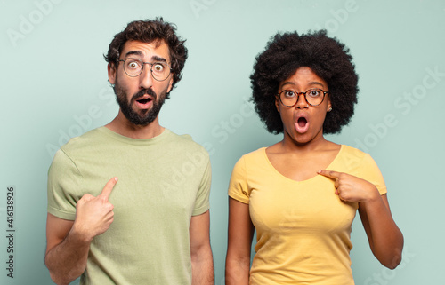 Obraz na plátne multiracial couple of friends looking shocked and surprised with mouth wide open