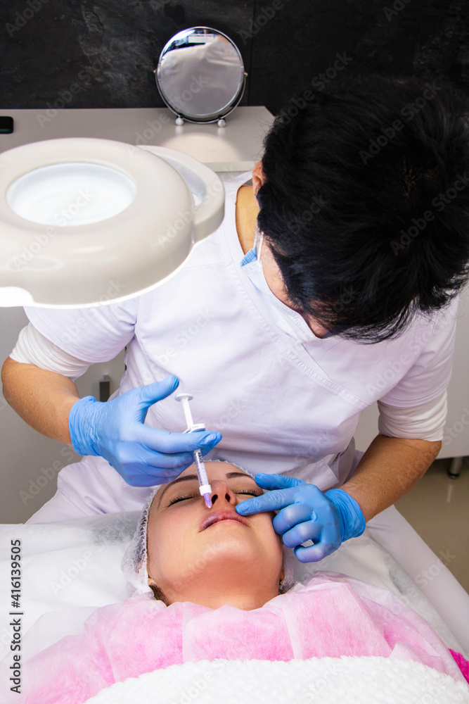 Cosmetology, lip augmentation, beauty injections in a beauty salon, close up