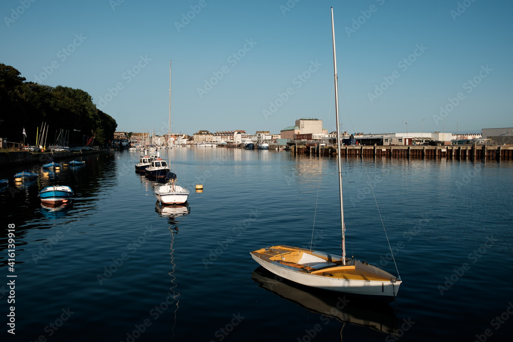 Small boats in Weymouth's harbor in a sunny morning. Yellow boat.