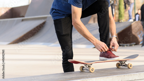 Unrecognizable skateboarder lacing skating shoes