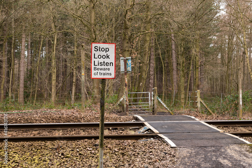 Sign advising members of the public to Stop Look Listen for trains located next to a pedestrian level crossing