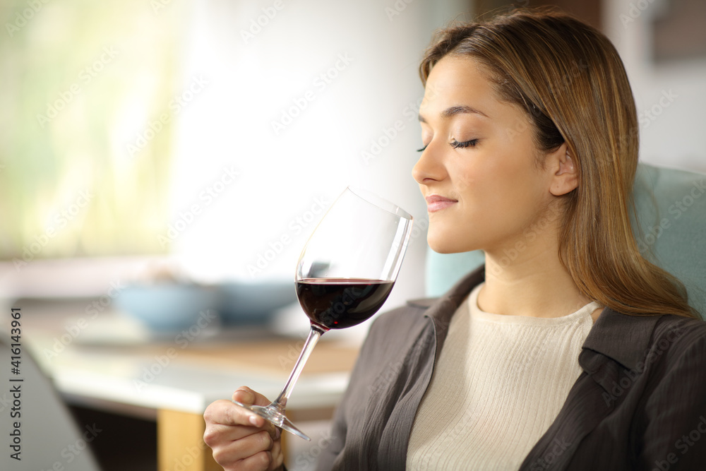 Serious woman smelling wine from cup at home Serious woman smelling wine from cup at home