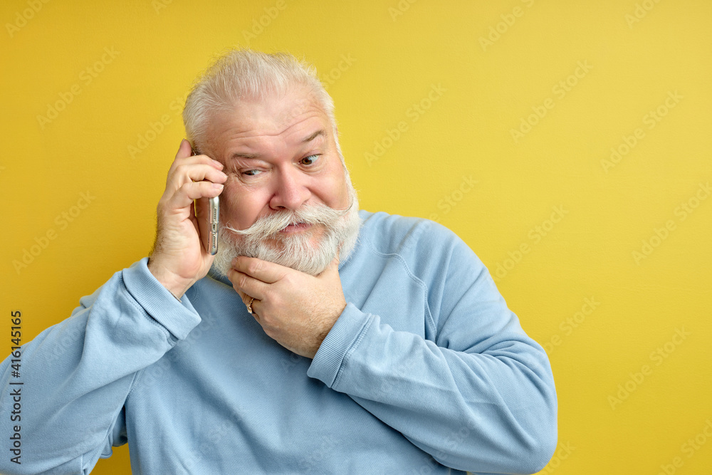 scared mature male touching chin, being surprised and scared to hear shocking news while talking on phone, cant believe in disaster, isolated over yellow background. People and reaction scared mature male touching chin, being surprised and scared to hear shocking news while talking on phone, cant believe in disaster, isolated over yellow background. People and reaction