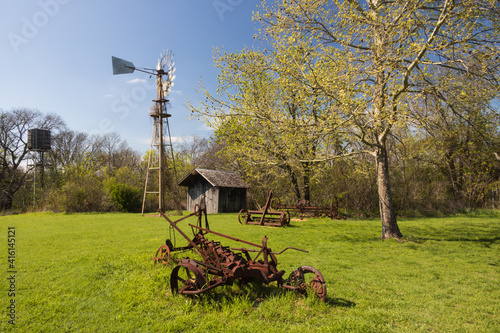 Obraz na plátně Old rusty farm equipment and tractor by a barn