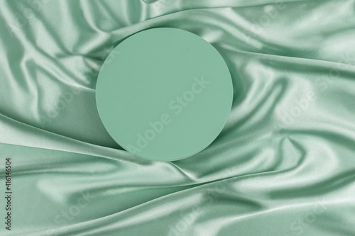 Geometric platform podium on light green silk satin background. Blank minimal cylinder form mock up background for cosmetic product presentation photo