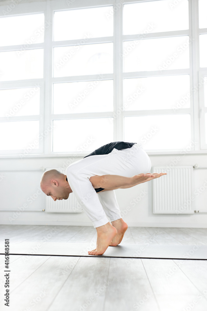 Man Yoga Practice Pose Training Concept, Doing Complex Pose Training, Man Standing On His Tiptoes Keeping Balance. Indoors Alone. Healthy Lifestyle Concept Man Yoga Practice Pose Training Concept, Doing Complex Pose Training, Man Standing On His Tiptoes Keeping Balance. Indoors Alone. Healthy Lifestyle Concept