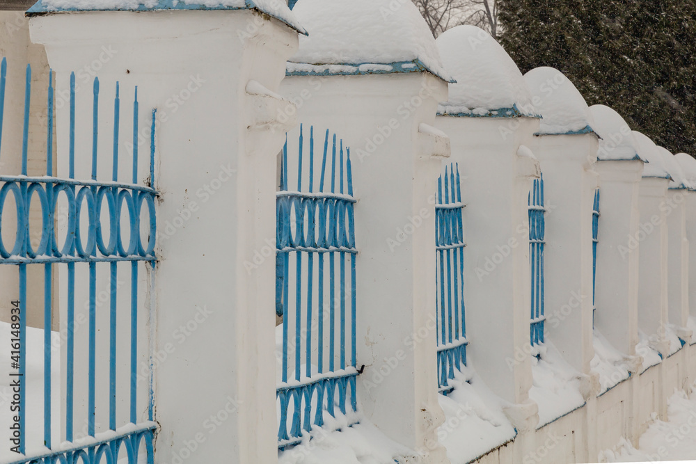 Obraz premium Stone fence of the church covered with snow caps