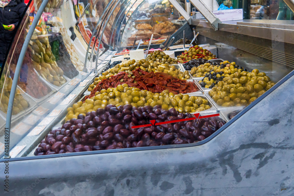 Assortment of colorful marinated olives and peppers behind a glass window on a food farmer's market. Pickled olives on Naschmarkt, Vienna ready to buy or sell.  Street market atmosphere.