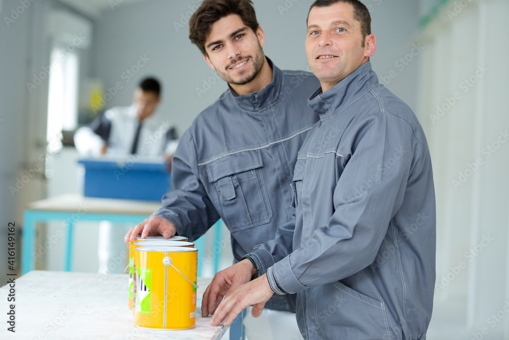 portrait of two professional decorators with tins of paint portrait of two professional decorators with tins of paint