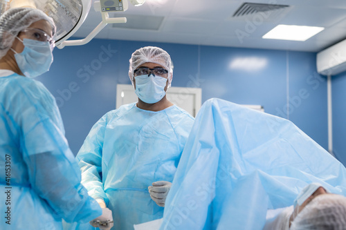 Young female assistant and male surgeon looking at screen of medical equipment