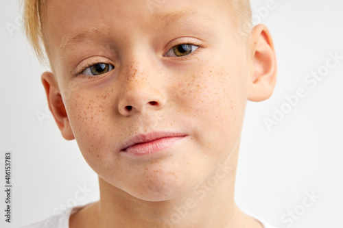 close-up portrait of freckled kid boy looking at camera, caucasian teenager boy 10 years old posing, isolated over white background