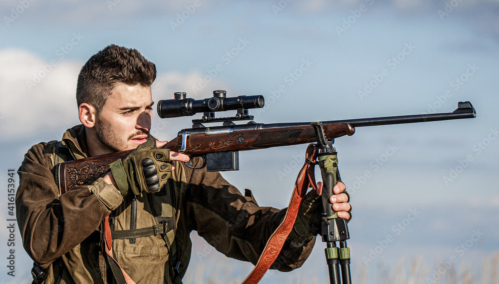Fototapeta premium Hunter with hunting gun and hunting form to hunt. Hunter is aiming. Shooter sighting in the target. The man is on the hunt. Hunt hunting rifle. Hunter man. Hunting period. Male with a gun