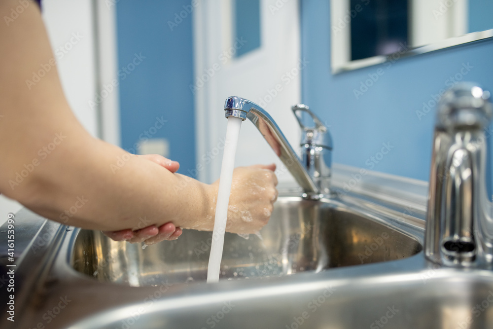 Young female assistant, nurse or surgeon washing hands over one of two sinks Young female assistant, nurse or surgeon washing hands over one of two sinks