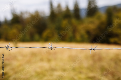 A closeup shot of a barbed metal wire with a mountain on the background photo