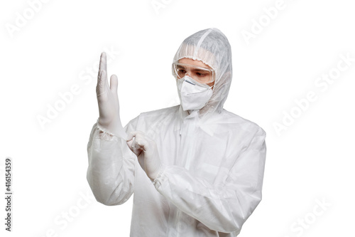 A doctor in chemical protection and a mask puts latex, rubber gloves on his hands. White isolated background.