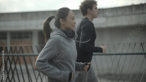 Sport couple jogging together in urban environment. Young people jogging together at fitness training outdoor. Man and woman at sport training together. Sport and urban concept.