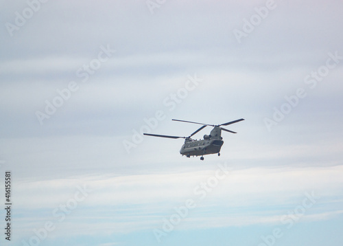 RAF Chinook UH-1 helicopter flying low in a cloudy blue grey and white winter sky
