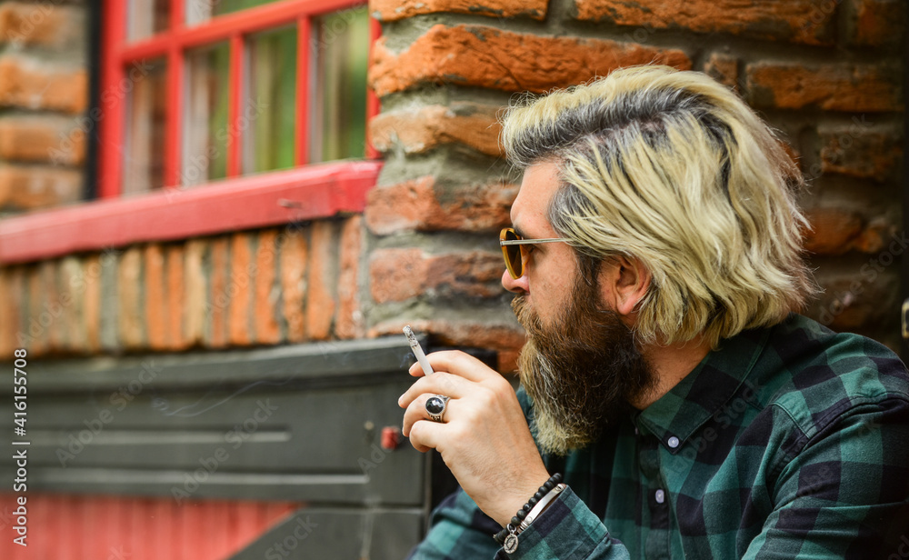 looking away. man smoking a cigarette. business man in glasses smoking cigarette on street. go out for smoke break. Handsome stylish man smoking outside in urban setting. hipster lifestyle