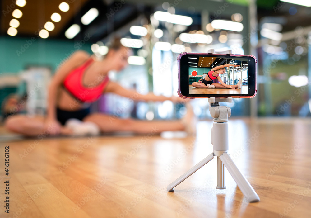 Obraz premium Stretching coach performs a fitness workout online via a smartphone