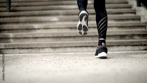 View of female legs in sportswear getting ready for a morning jogging around the town. Urban city lifestyle. Active woman runner exercising outside. 