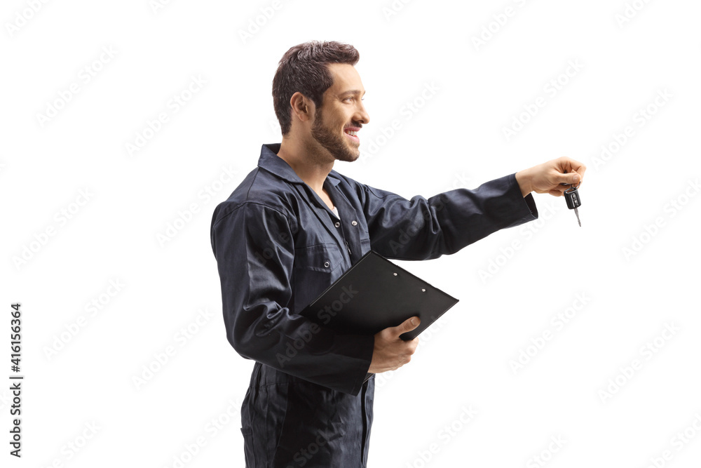 Mechanic in overalls holding a clipboard and car keys Mechanic in overalls holding a clipboard and car keys
