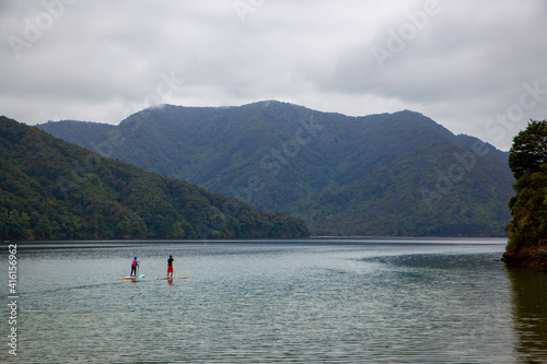 Paddle boarders make their way around the coastline on a calm summers day, Marlborough Sounds, New Zealand