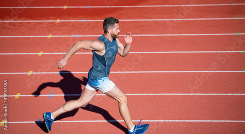 sportsman male in sportswear run fast sprinting on running track, distance