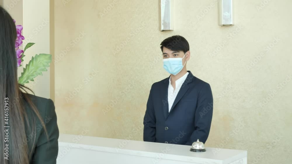 Asian Business woman wear surgical mask and Return the keycard with hotel receptionists at lobby. New Normal, Business travel. Shot slow motion Asian Business woman wear surgical mask and Return the keycard with hotel receptionists at lobby. New Normal, Business travel. Shot slow motion