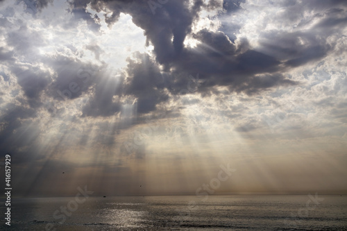 Photo Cloudy sky with holes and sunbeams over sea