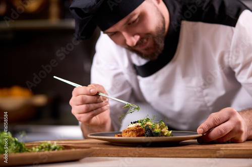 Fotografia chef dressing salad with fresh greens, adding finishing touch on dish before it