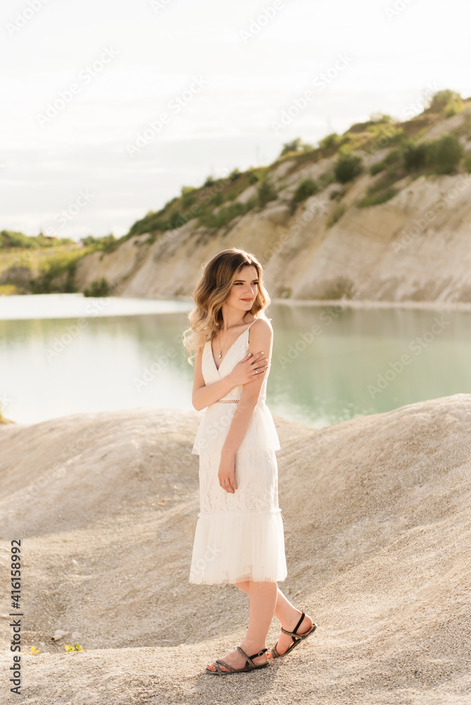 Portrait of a beautiful girl in a white dress with hair and makeup on the background of the sea