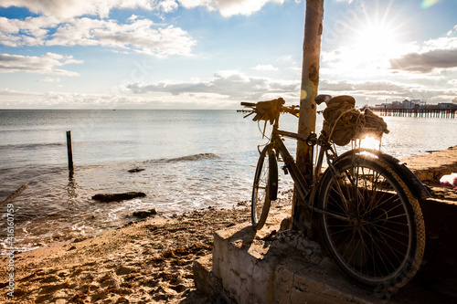 An old bicycle stands on the seashore.