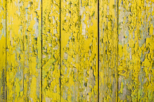 Yellow wooden fence with cracks and old paint.