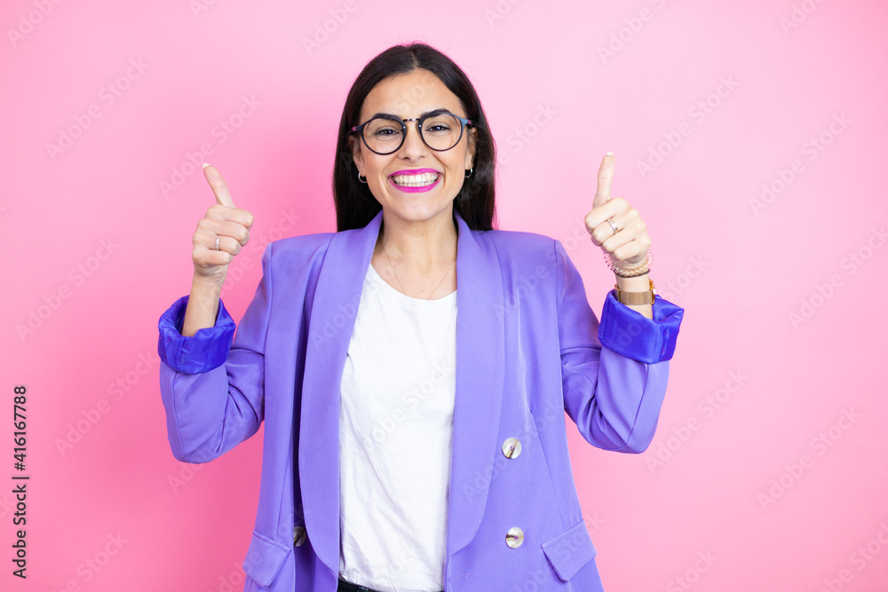 Φωτογραφία Young business woman wearing purple jacket over pink background success sign doing positive gesture with hand, thumbs up smiling and happy