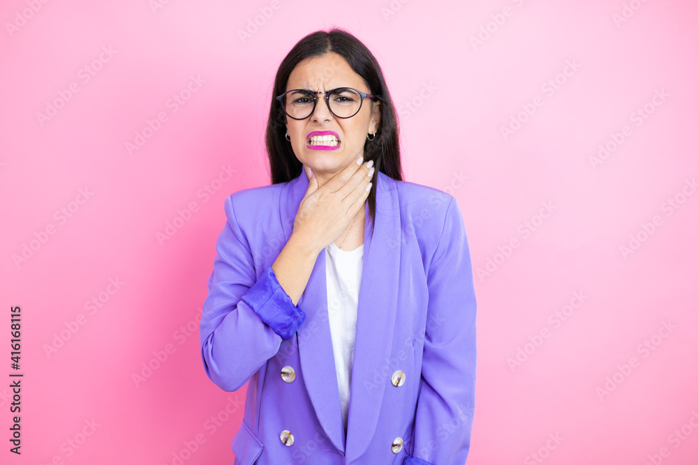 Young business woman wearing purple jacket over pink background touching painful neck, sore throat for flu, clod and infection