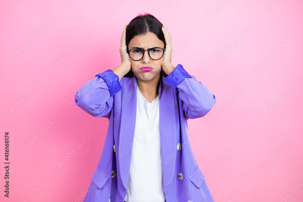 Young business woman wearing purple jacket over pink background thinking looking tired and bored with hands on head Young business woman wearing purple jacket over pink background thinking looking tired and bored with hands on head