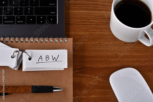 On the desk there is a laptop  a cup of coffee  and a word book with the word ABW written on it. It was an abbreviation for the financial term Activity Based Working.