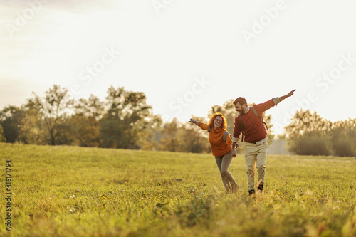 Young happy couple in love holding hands and running on meadow. It's a beautiful sunny autumn day. Freedom.