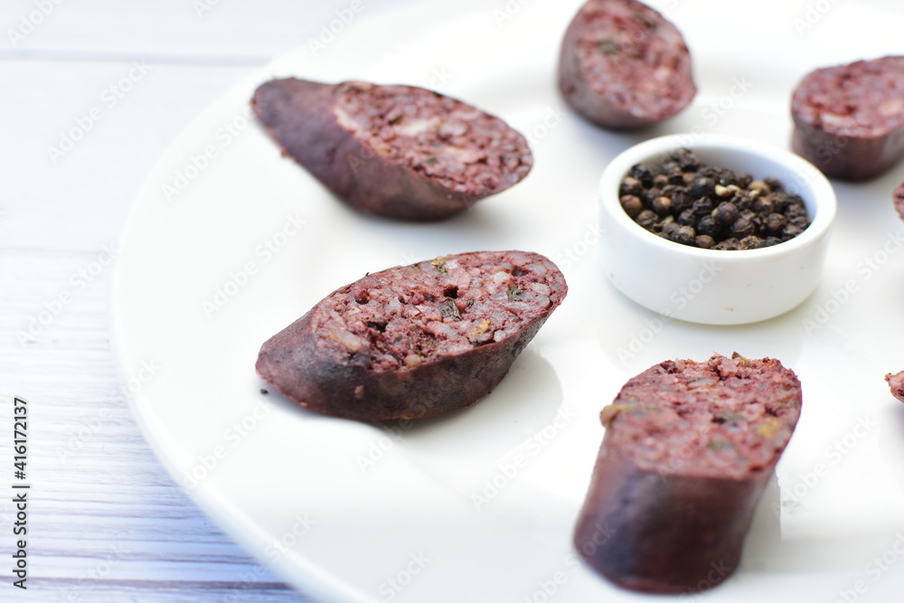 Morcilla Antioqueña, traditional Colombian sausage, covered with lemon and pepper on wooden background