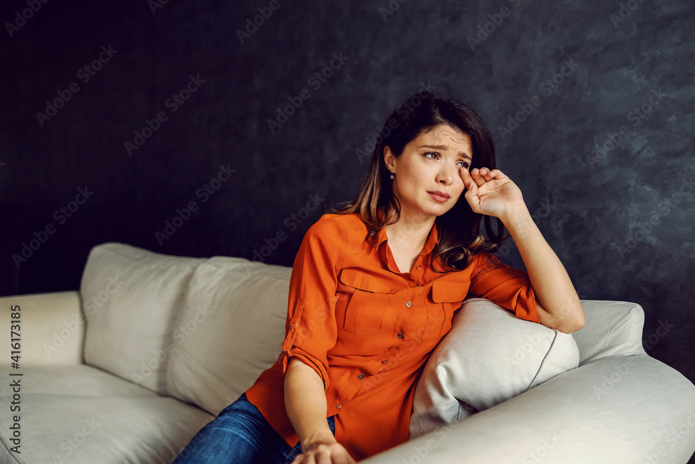 Woman in depression sitting on sofa and crying. She is very lonely and hopeless. Woman in depression sitting on sofa and crying. She is very lonely and hopeless.
