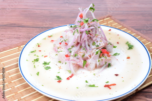Traditional Peruvian ceviche with fish, onion, lemon, chili peppers, coriander, salt and pepper on wooden background
