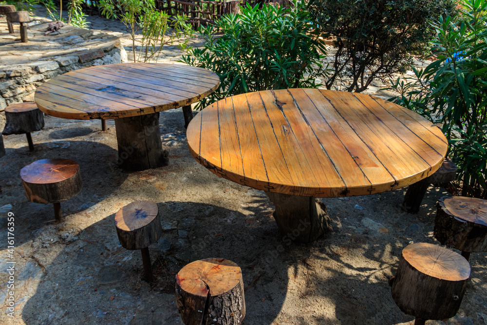 Empty rustic round wooden table and stools in park in Kemer, Turkey Empty rustic round wooden table and stools in park in Kemer, Turkey