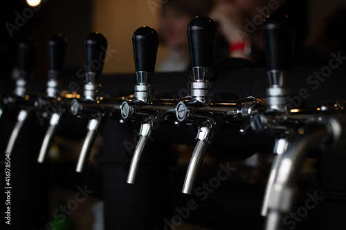 Partially blurred silvery bar beer taps in pub