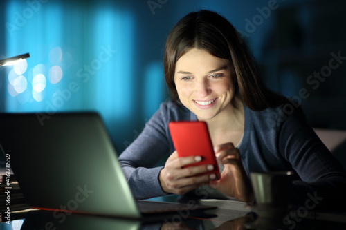 Woman with laptop checking phone in the night
