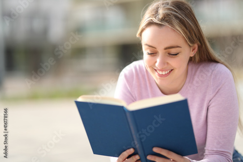 Happy teen reading a paper book in a park