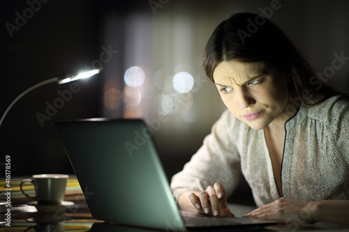 Suspicious woman checking laptop content in the night photo